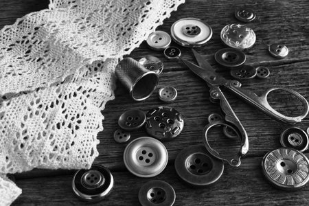 A black and white image of vintage buttons with scissors and delicate old lace.