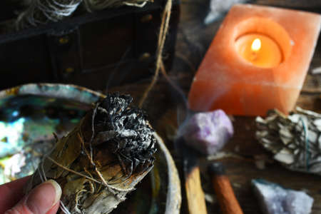 A close up image of a burning white sage smudge stick and healing crystals.の写真素材