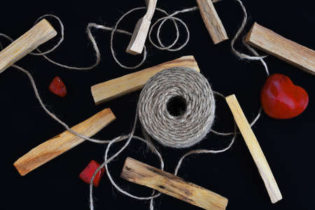 A top view image of healing smudge sticks and red jasper crystals on a black background.