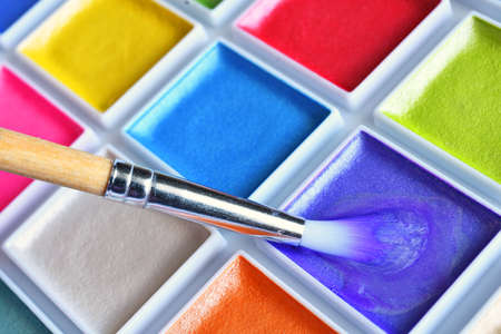 A close up image of brightly colored water paints and paint brushes.の写真素材