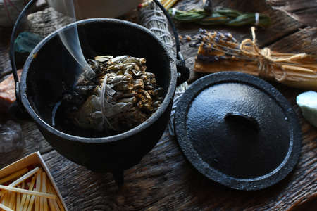 A close up image of a burning white sage smudge stick, healing crystals, and sacred feather.の写真素材