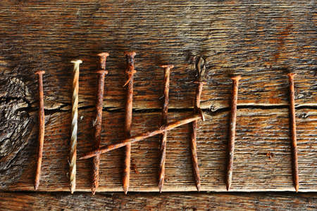 A close up image of several old and very rusted nails on a dark wooden table.の写真素材