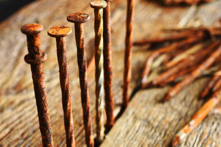 A close up image of several old and very rusted nails on a dark wooden table.の写真素材
