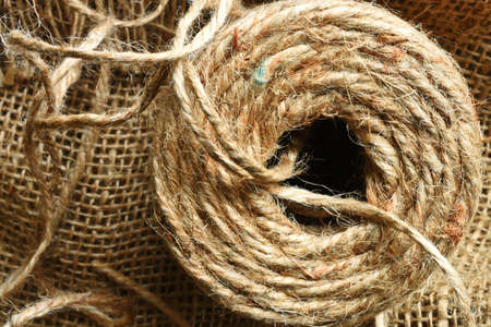 A close up image of coils of beige burlap string on burlap fabric.