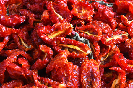 A close up image of sun dried cherry tomatoes with dried basil leaves.
