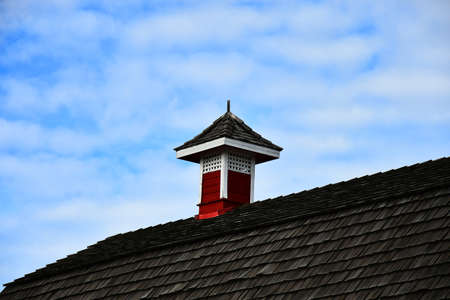 An image of a single red steeple on top of an old barn roof.の写真素材
