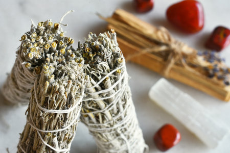 A top view image of three white sage smudge sticks and healing red jasper crystals on a white table top.の写真素材