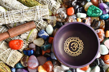 A top view image of a purple meditations singing bowl with white sage smudge sticks and healing crystals.の写真素材