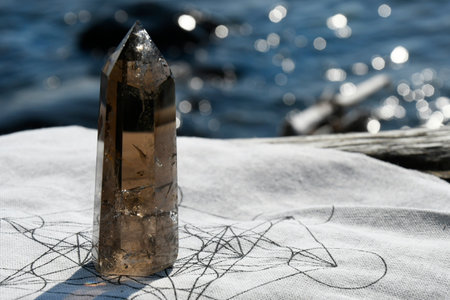 A close up image of a large smokey quartz crystal tower on a large piece of driftwood.の写真素材