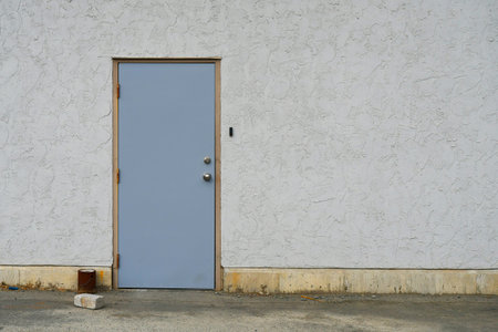 Closed and locked industrial steel door on an exterior wall.