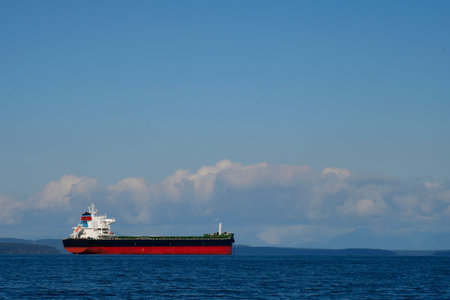 A large red and black cargo ship in mid harbor waiting to off load its cargo.の写真素材