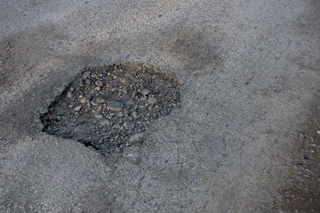An image of a very deep pot hole in the middle of a well traveled road.