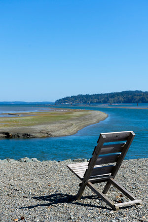 An image of a single old wooden chair with a beautiful ocean view on a sunny summer day.の写真素材