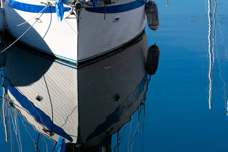 A crystal clear water reflection of the hull of a boat moored to a dock.の写真素材