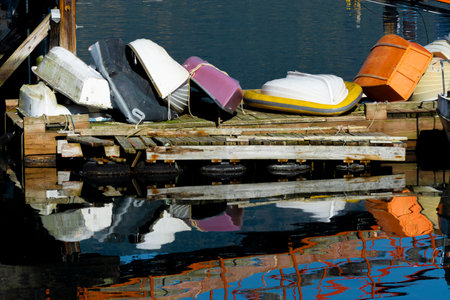 An image of several small row boats and fishing boats stacked on a wooden pier creating a colorful...