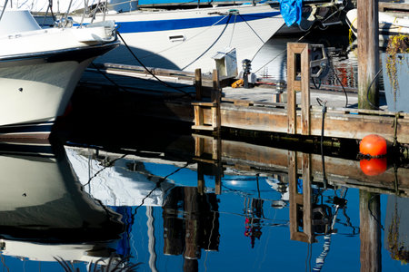 An image of a white passenger boat and wooden dock reflecting in clear blue ocean water.