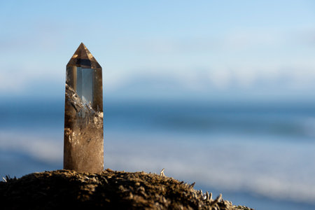 A close up image of a healing smoky quartz crystal tower with the blue Pacific Ocean in the background.の写真素材