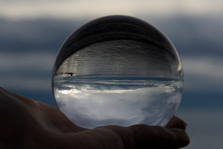 A close up image of a photographic lens ball showing an inverted image of the Pacific Ocean on a...
