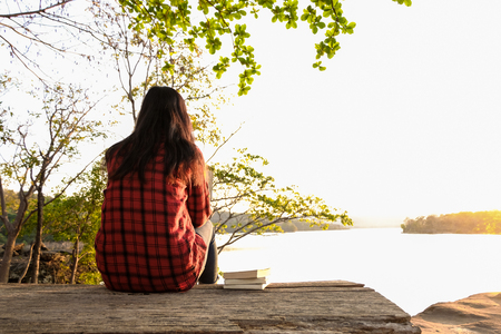 Relaxing moments, Young woman reading a book by the lake. Solo relaxation, color of Hipster Tone.の写真素材