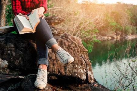 Relaxing moments, Young woman reading a book by the lake. Solo relaxation, color of Hipster Tone.の写真素材