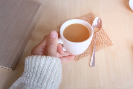 Relaxing moments, Cup of coffee and a book on wooden table in nature background, color of vintage tone and soft focus, winter morning concept.の写真素材