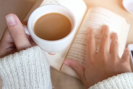 Relaxing moments, Cup of coffee and a book on wooden table in nature background, color of vintage tone and soft focus, winter morning concept.の写真素材