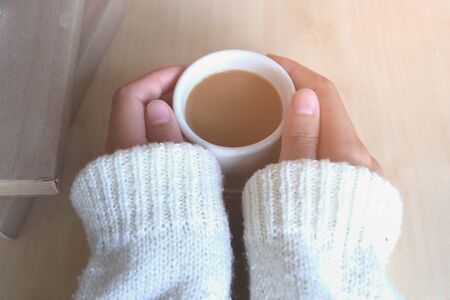 Relaxing moments, Cup of coffee and a book on wooden table in nature background, color of vintage tone and soft focus, winter morning concept.の写真素材