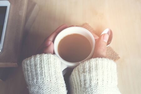 Relaxing moments, Cup of coffee and a book on wooden table in nature background, color of vintage tone and soft focus, winter morning concept.の写真素材