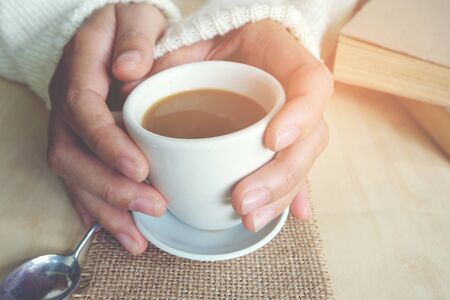 Relaxing moments, Cup of coffee and a book on wooden table in nature background, color of vintage tone and soft focus, winter morning concept.の写真素材