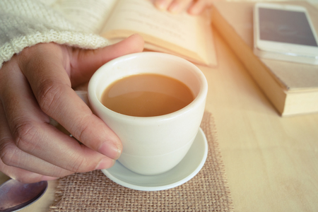 Relaxing moments , Cup of coffee and a book on wooden table in nature background, color of vintage tone and soft focus, winter morning concept.の写真素材