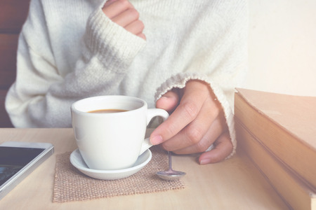 Relaxing moments , Cup of coffee and a book on wooden table in nature background, color of vintage tone and soft focus, winter morning concept.の写真素材