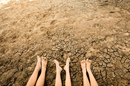 Barefoot on land with dry and cracked ground.  Affected of global warming made climate change. Water shortage and drought concept.の写真素材