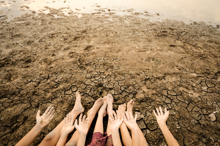 Barefoot on land with dry and cracked ground.  Affected of global warming made climate change. Water shortage and drought concept.の写真素材