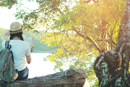 Young girl reading a book and nature background, traveling Relax time on holiday concept travel, color of vintage tone and soft focus.の写真素材