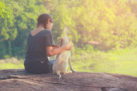 A girl and her dog enjoying travel in nature background  the sunset, color of vintage tone and soft focusの写真素材