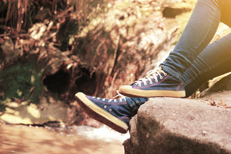 Traveller feet in sneakers surrounded at natural beauty, concept travel, color of vintage tone and soft focus.の写真素材