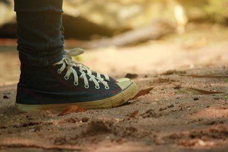 Traveller feet in sneakers surrounded at natural beauty, concept travel, color of vintage tone and soft focus.の写真素材