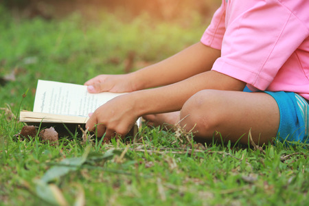 Little boy read a book in the green lawn outdoors, Relax time, selective soft focus.の写真素材