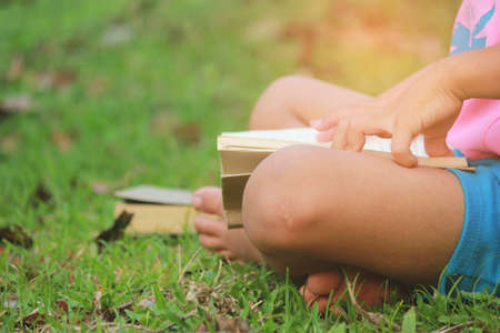 Little boy read a book in the green lawn outdoors, Relax time, selective soft focus.の写真素材