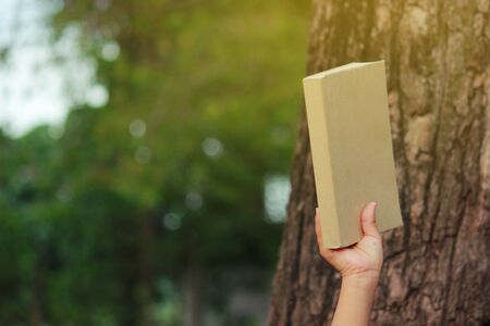 Little Boy with book siting under the big tree, selective soft focus.の写真素材