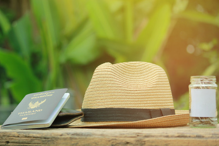 Saving money for vacation concept, glass coins container , Old cameras, hats and a book and nature background.の写真素材