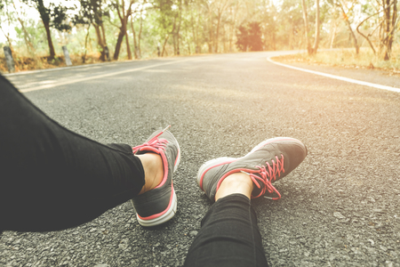 Runner athlete standing on road towards sun. Concept of new start, travel, freedom etc. Close up cropped low angle photo of shoe of athlete.の写真素材