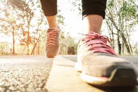 Runner athlete standing on road towards sun. Concept of new start, travel, freedom etc. Close up cropped low angle photo of shoe of athlete.の写真素材