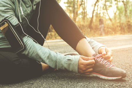 Runner athlete tying shoelaces Preparing to run to begin starting on the road, sunset light.の写真素材