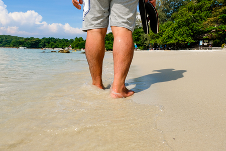 Leg of young men walking along wave of sea water and sand on the beach in tropical island with carefree and relaxing attitude - Travel Concept.の写真素材