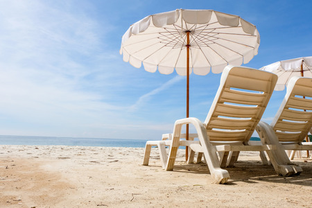 Lounge chairs with sun umbrella on a beach. Sun of summer time on sky and sand of beach relaxation landscape viewpoint. Ocean nature tranquility, Thailand.の写真素材