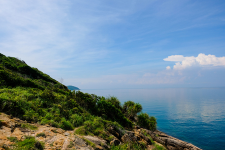 sea horizon with rocky shore cliffs and sun light blue sky background. Sea waves crashing on rocks, Samed, Thailandの写真素材