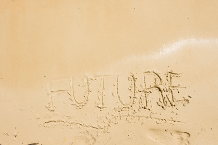 Text FUTURE drawn on a sand of beach with the wave of the sea in the bright sunlight.の写真素材