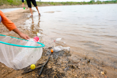 Young volunteers with garbage bags cleaning area in dirty beach of the lake, People and ecology. Volunteer concept.の写真素材