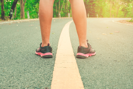 Ready for a sprint. Runner athlete standing on road towards sun. Concept of new start, travel, freedom etc. Close up cropped low angle photo of shoe of athlete.の写真素材
